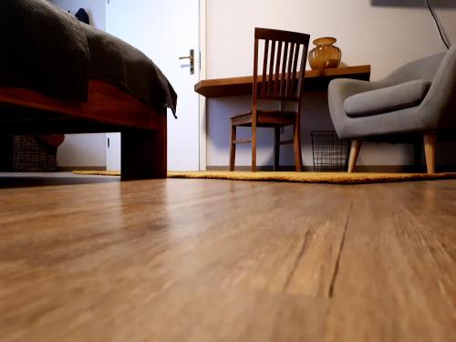 a living room with a wooden floor and a chair at Pension am Park in Oschatz