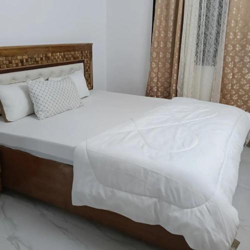a bed with white sheets and pillows in a room at Shivoham holiday villa in Dapoli