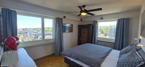 a bedroom with a ceiling fan and large windows at Lake View See & Bergsicht free parking in Kreuzlingen