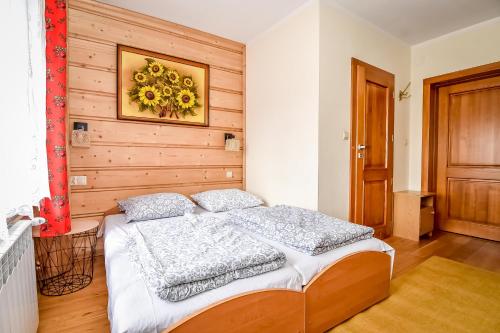 a bedroom with a bed with a wooden wall at Pod Wyciągiem Harenda in Zakopane