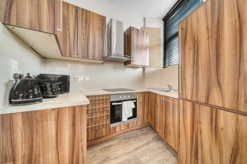 a kitchen with wooden cabinets and a stove at Heart of Shoreditch in London
