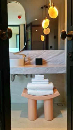 a pile of towels on a table in a bathroom at The SACHA Apart-Hotel Thonglor Sukhumvit Bangkok in Bangkok