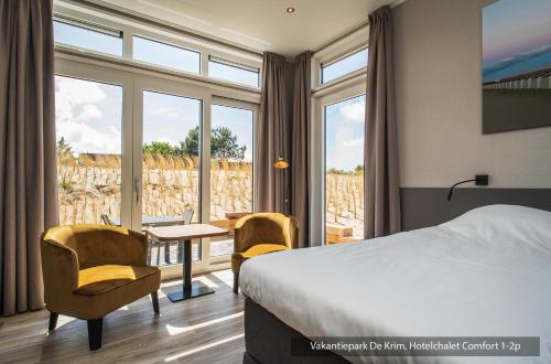 a hotel room with a bed and a table and chairs at Vakantiepark De Krim Texel in De Cocksdorp
