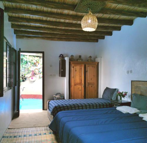 a bedroom with two beds and a door to a pool at Dar Lala Zhour in Aïn Bouchrik