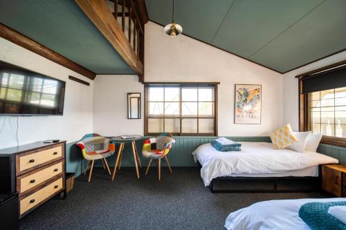 a bedroom with two beds and a table and chairs at The Bears Lodge in Hakuba