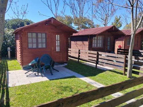 a cabin with a fence and two chairs in front of it at CirceMed Glamping in San Felice Circeo
