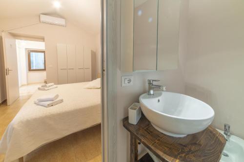 a bathroom with a sink next to a bed at Sardinian Gallery S'Iscola in Bosa