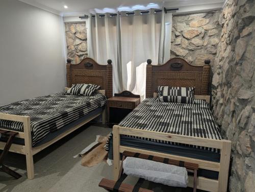 a bedroom with two beds and a stone wall at Potjesberg Lodge in Laudina