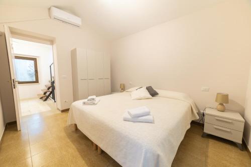 a bedroom with a white bed with two towels on it at Sardinian Gallery S'Iscola in Bosa