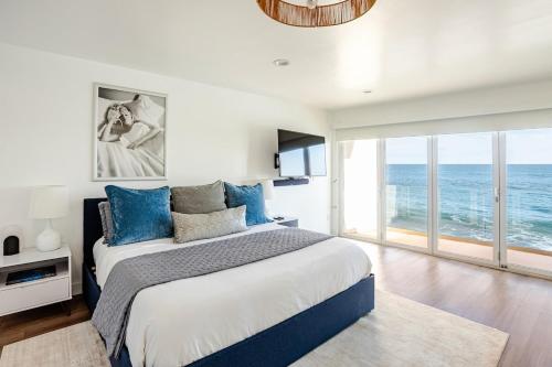 a bedroom with a large bed with blue pillows at Malibu Beachfront Home with Rock Spa Ocean Views & Huge Deck in Malibu