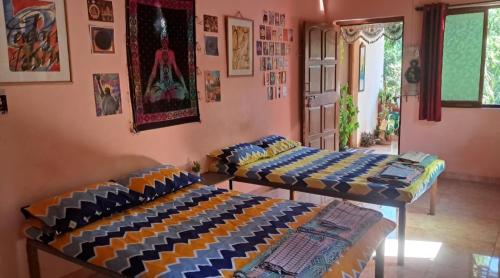 two beds in a room with paintings on the wall at Bageecha B&B- V A A Y U in Alībāg