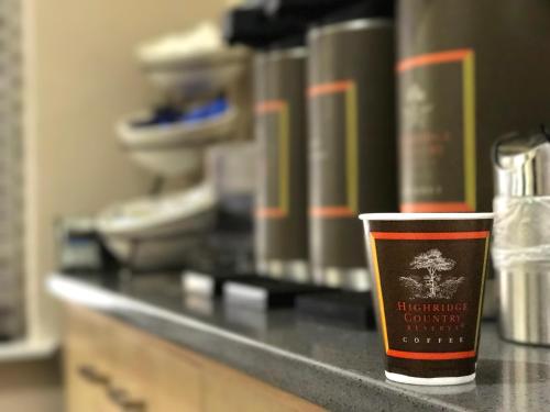 a cup of coffee sitting on a counter with books at Country Inn & Suites by Radisson, Dalton, GA in Dalton