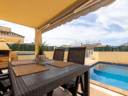 a table and chairs on a patio with a swimming pool at Holiday Home Flamenc 2 by Interhome in Riumar