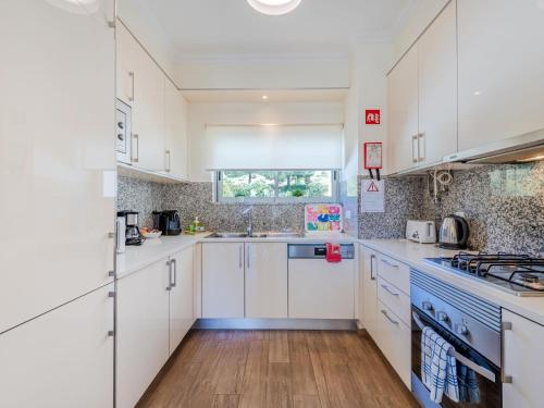 a kitchen with white cabinets and blue appliances at Apartment Jardins Marina T2 - VIP Properties by Interhome in Albufeira