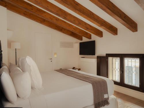 a white bedroom with a large bed and a tv at Portella Palma in Palma de Mallorca