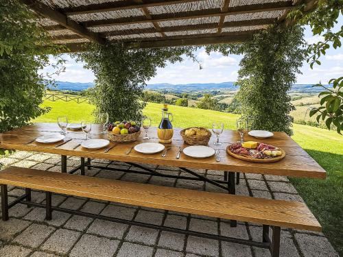 a wooden table with baskets of fruit and wine glasses at Apartment Torrenieri by Interhome in Vergelle