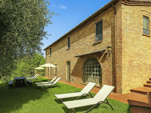 two lawn chairs and an umbrella in front of a brick building at Apartment Monteroni by Interhome in Vergelle