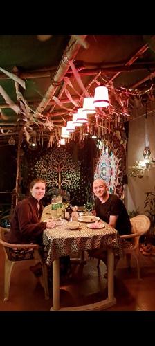 two women sitting at a table in a room at Bageecha B&B- V A A Y U in Alībāg