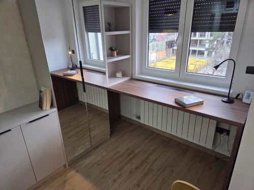 a desk in a room with two windows and a desk with a lamp at Apartmani Optimist in Valjevo