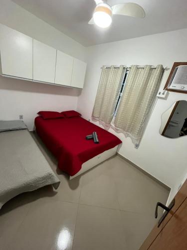 a bedroom with a red bed in a white room at Sonho Meu in Saquarema