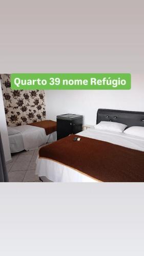 two beds in a room with a sign that reads quater to home refuge at Pousada Beira Mar in Matinhos