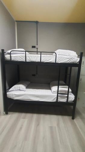 two bunk beds in a room with white sheets at Yellow Monkey Hostel Uluwatu in Uluwatu