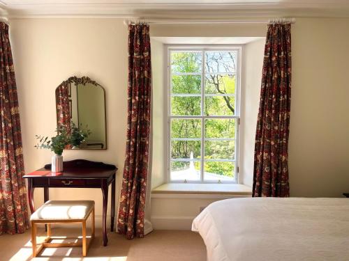 a bedroom with a window and a table and a mirror at The Coach House in Stirling