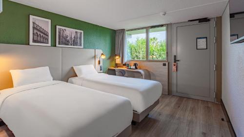two beds in a hotel room with green walls at Campanile NATURE - Bayonne in Bayonne