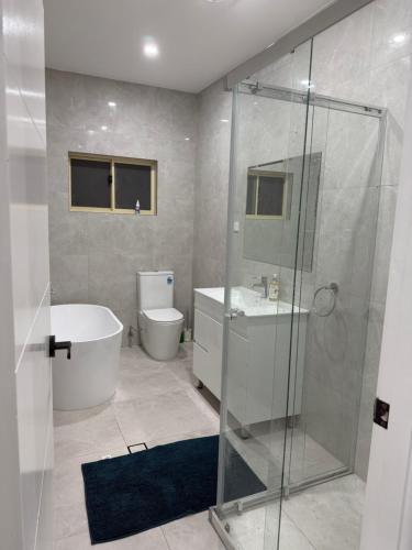 a bathroom with a shower and a tub and a toilet at Second Home - A modern 4 Bedrooms House in Blacktown