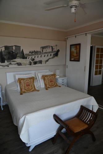 a bedroom with a large white bed with a chair at Pavillon de Lubéron in Lauris