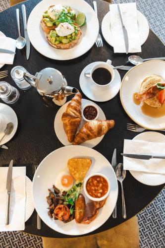 a table with plates of breakfast food on it at Hotel Collingwood BW Signature Collection in Bournemouth