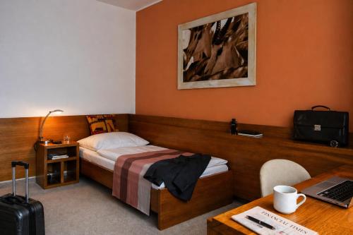 a hotel room with a bed and a desk with a laptop at Afrika Hotel Frýdek-Místek in Frýdek-Místek
