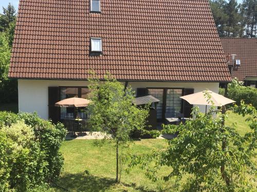 a house with umbrellas in front of a yard at Ferienwohnungen Wagner am Brombachsee in Pleinfeld