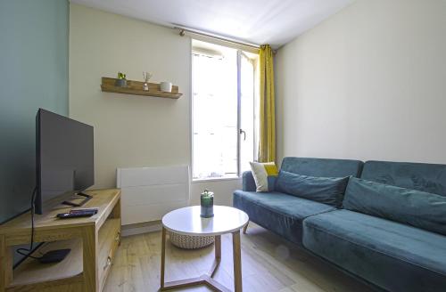 a living room with a blue couch and a tv at Le Cocon de Nuit Normande in Étretat