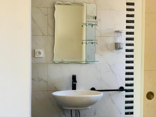 a bathroom with a white sink and a mirror at Odyssée Résidence in Mahajanga
