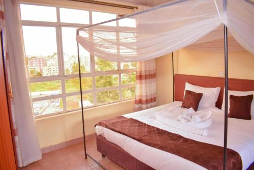 a bedroom with a canopy bed and a large window at Greenvale Hotel 1BR Along Kamiti Road in Kiambu