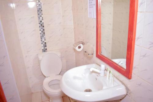 a bathroom with a sink and a toilet and a mirror at Greenvale Hotel 1BR Along Kamiti Road in Kiambu