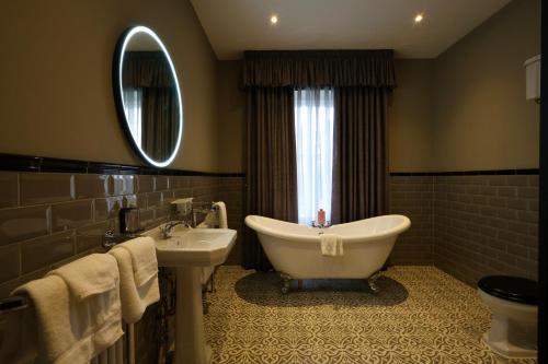 a bathroom with a tub and a sink and a mirror at Y Seren Hotel & Restaurant in Carmarthen