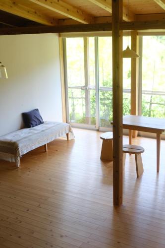 a room with a bed and a table and windows at Lotus Retreat ロータスリトリート 高知空港から車で30分 山のふもとの一棟貸しコテージ in Kami
