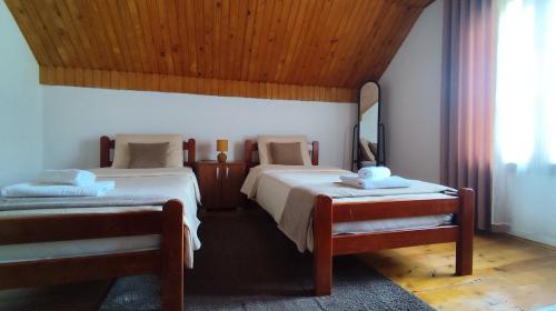 a bedroom with two beds and a wooden ceiling at Nest for rest in Mojkovac