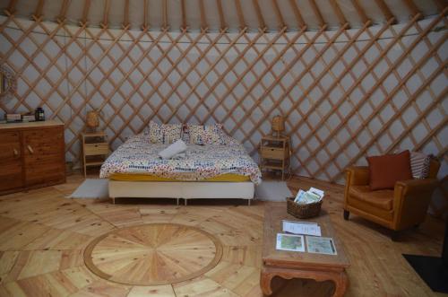 a room with a bed and a chair in a yurt at Les insolites de la Ferme de Froidefontaine in Havelange