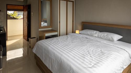 a bedroom with a large white bed and a bathroom at Patera Living in Sempidi