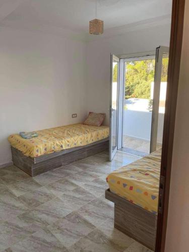 a bedroom with two beds and a sliding glass door at Haouaria PANTELLERIA in Sidi Amor