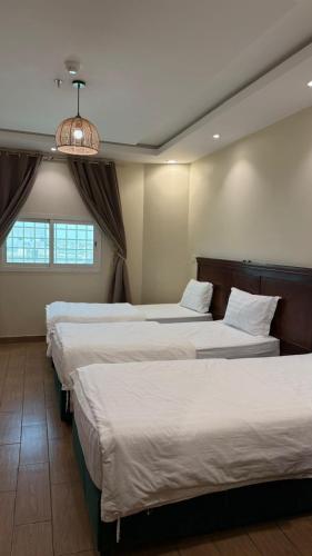 a row of four beds in a hotel room at ريف سويت للشقق المخدومة in Al Namas