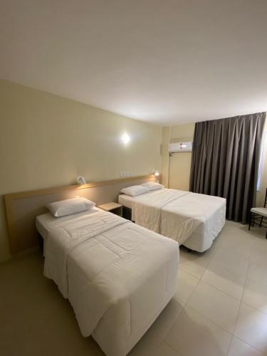 a hotel room with two beds and a window at Klein Ville Marquês in São Leopoldo