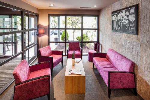 a waiting room with pink furniture and windows at Hotel Loreak in Bayonne