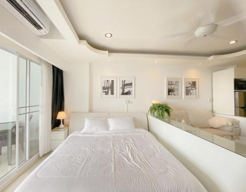 a white bedroom with a large bed and a couch at Beautiful Sea View Cozy Condo in Pattaya South