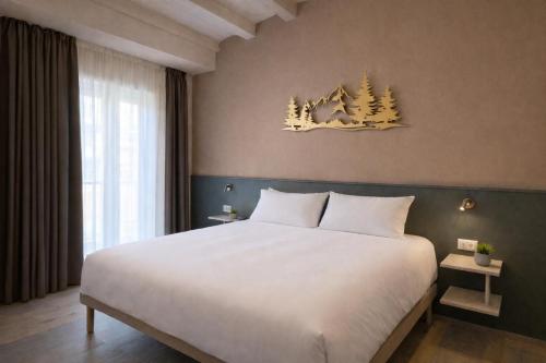 a bedroom with a large white bed and trees on the wall at Il Ritrovo Rooms in Petralia Sottana