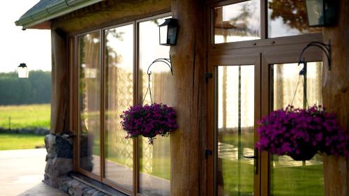 two hanging baskets of purple flowers on a building at Metsapiiga Talu in Vilina