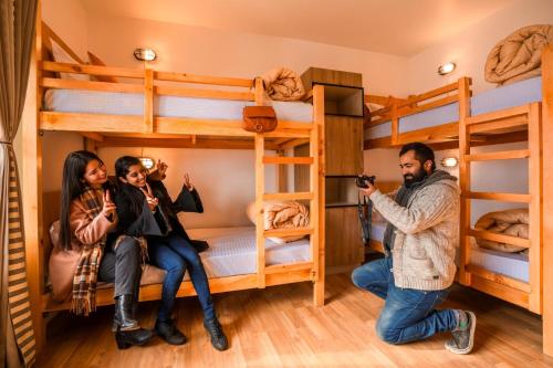 a man taking a picture of three people in a room with bunk beds at PACK Sissu in Sissu